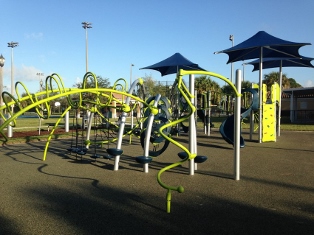 curvy yellow playground amenities with blue shade structures